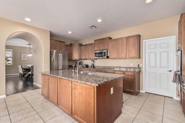 3964 E Hummingbird Ln, Phoenix, AZ 85050 - kitchen featuring appliances with stainless steel finishes, a sink, dark stone countertops, arched walkways, and baseboards