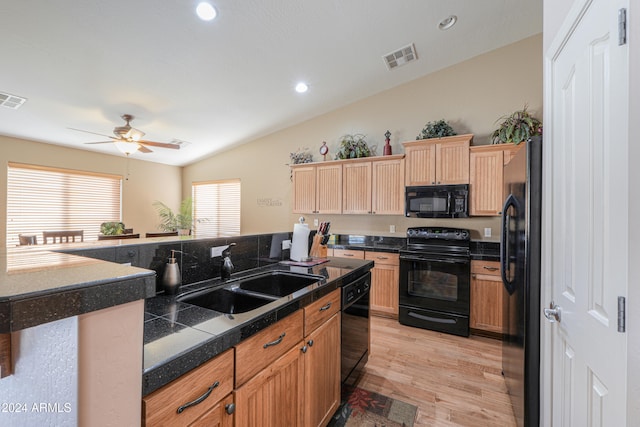 kitchen featuring lofted ceiling, black appliances, sink, light wood-type flooring, and ceiling fan