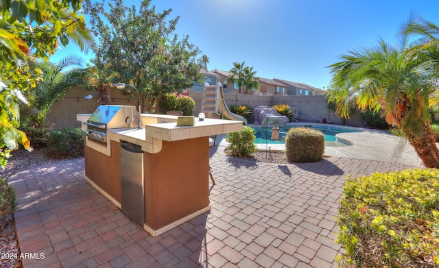 view of patio featuring area for grilling, a fenced in pool, and a bar