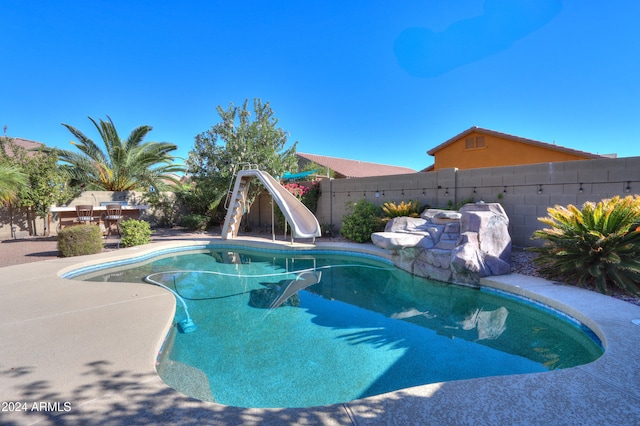 view of swimming pool with a water slide and a patio area