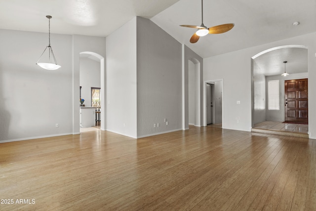 1135 W Sea Fog Dr, Gilbert, AZ 85233 - unfurnished living room with arched walkways, ceiling fan, wood finished floors, and high vaulted ceiling