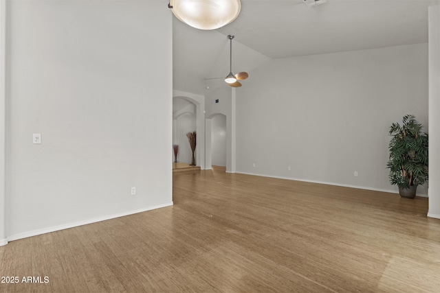 1135 W Sea Fog Dr, Gilbert, AZ 85233 - unfurnished living room featuring arched walkways, vaulted ceiling, a ceiling fan, and wood finished floors