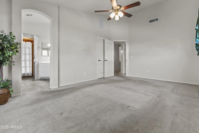 1135 W Sea Fog Dr, Gilbert, AZ 85233 - unfurnished living room featuring a ceiling fan, carpet floors, arched walkways, and a high ceiling