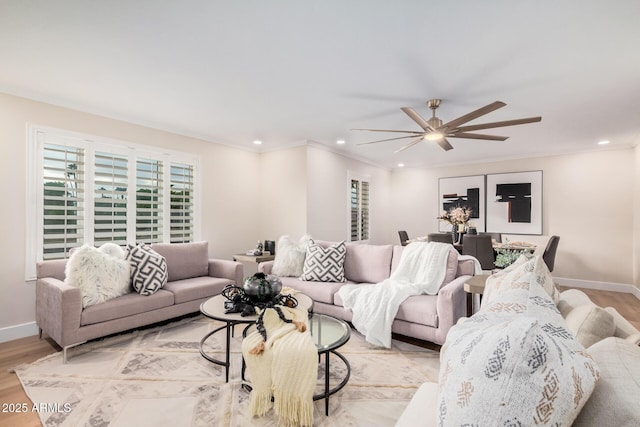 living room with crown molding, ceiling fan, and light hardwood / wood-style floors