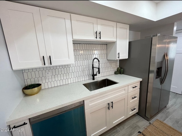 kitchen with light stone counters, stainless steel appliances, sink, and white cabinets