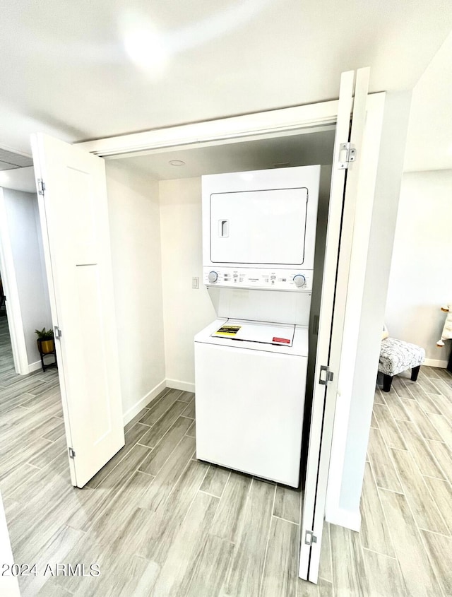 laundry room with light hardwood / wood-style flooring and stacked washer / drying machine