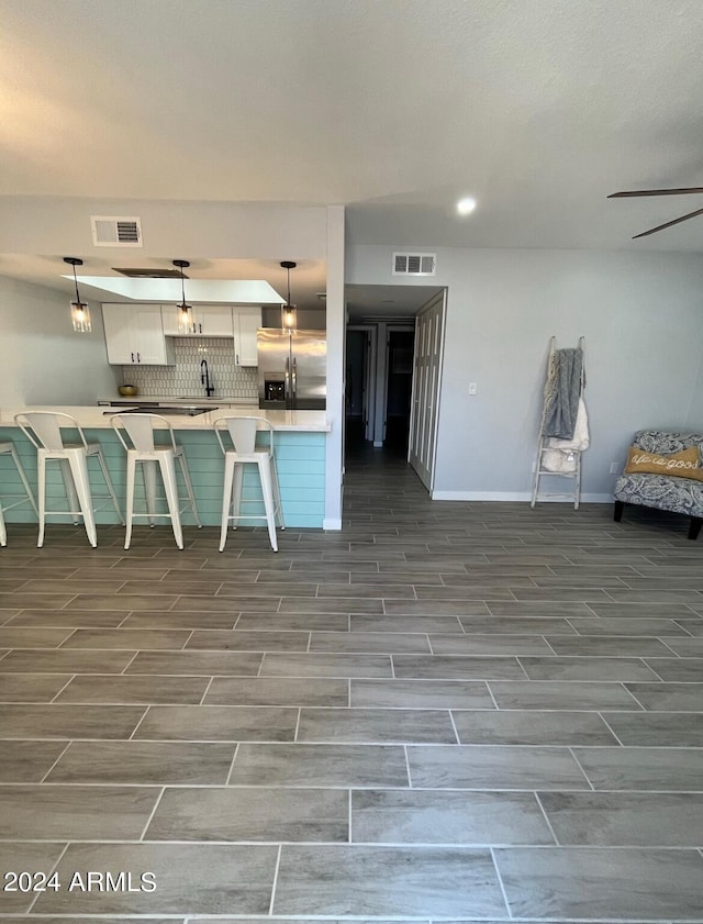 kitchen with white cabinetry, a breakfast bar, stainless steel refrigerator with ice dispenser, and pendant lighting