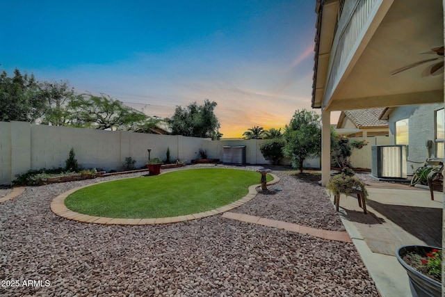 10745 W Beaubien Dr, Sun City, AZ 85373 - yard at dusk with a fenced backyard, central AC unit, a ceiling fan, and a patio