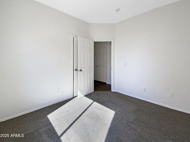 empty room with dark carpet and baseboards