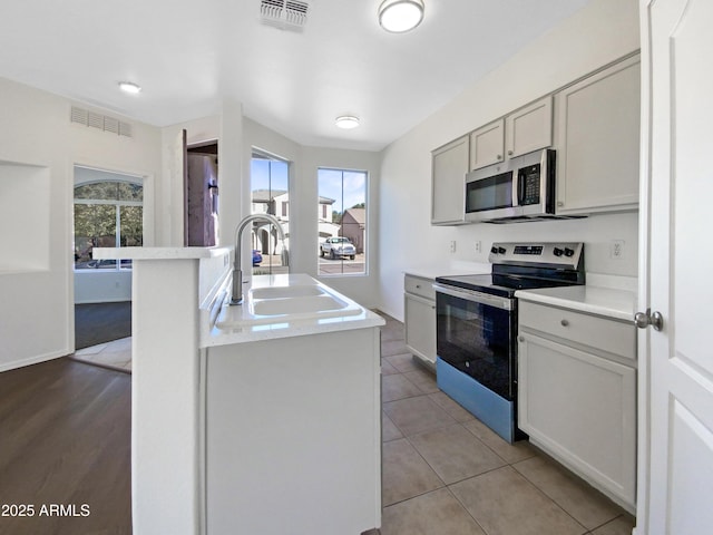 kitchen with appliances with stainless steel finishes, light countertops, visible vents, and a sink