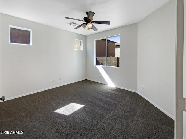 spare room featuring baseboards, visible vents, dark colored carpet, and a ceiling fan