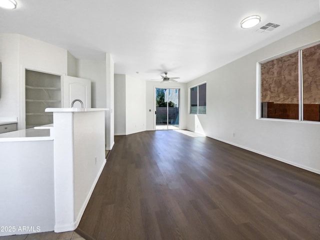 unfurnished living room featuring a ceiling fan, baseboards, visible vents, and dark wood-type flooring