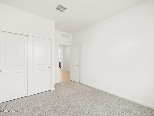 unfurnished bedroom with light colored carpet and a closet