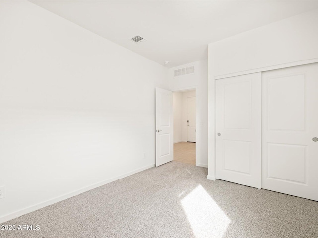 unfurnished bedroom with light colored carpet and a closet