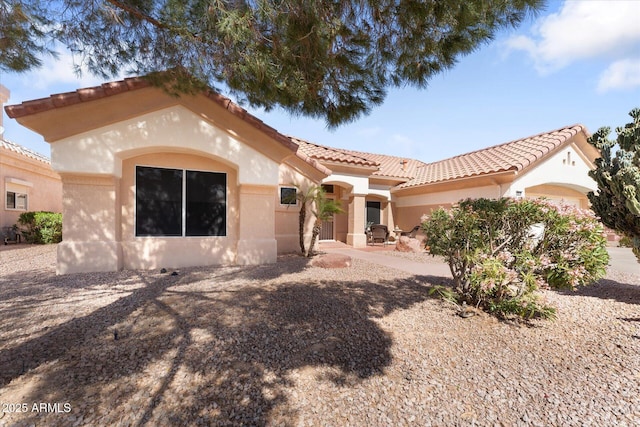 mediterranean / spanish-style house with stucco siding, a tiled roof, and a garage