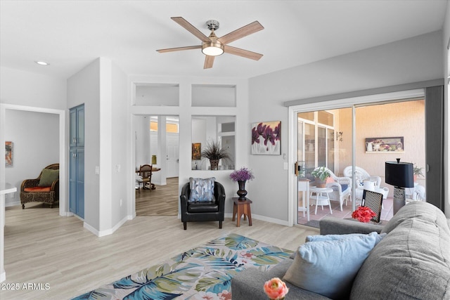 living area with baseboards, a ceiling fan, and light wood finished floors