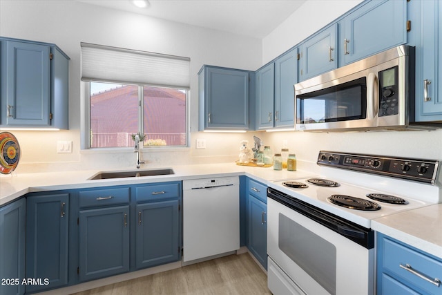 kitchen featuring blue cabinets, white appliances, light countertops, and a sink