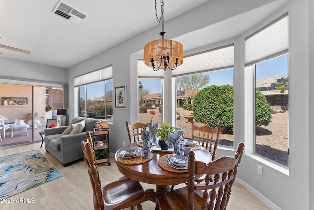 dining space with visible vents, baseboards, an inviting chandelier, and light wood finished floors