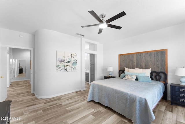 bedroom featuring visible vents, light wood-style flooring, ensuite bath, baseboards, and ceiling fan