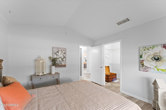 bedroom featuring visible vents, light wood-style flooring, baseboards, and lofted ceiling