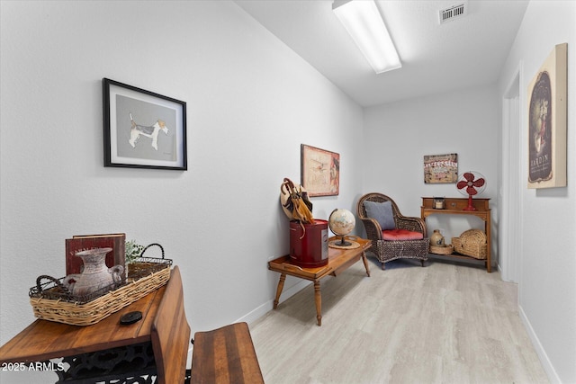 sitting room featuring baseboards, visible vents, and light wood-type flooring