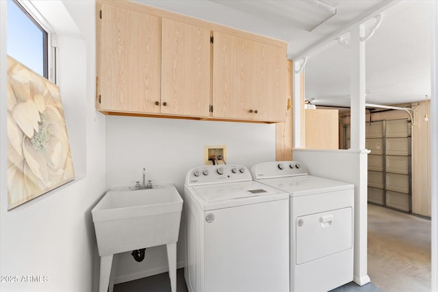 laundry room featuring washing machine and clothes dryer, cabinet space, and a sink