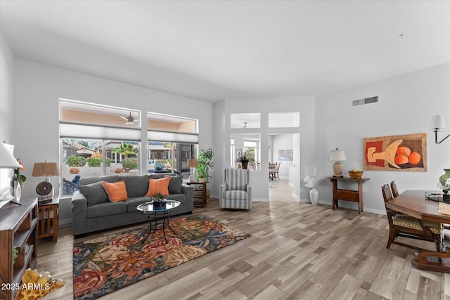 living room featuring a ceiling fan, wood finished floors, visible vents, and baseboards