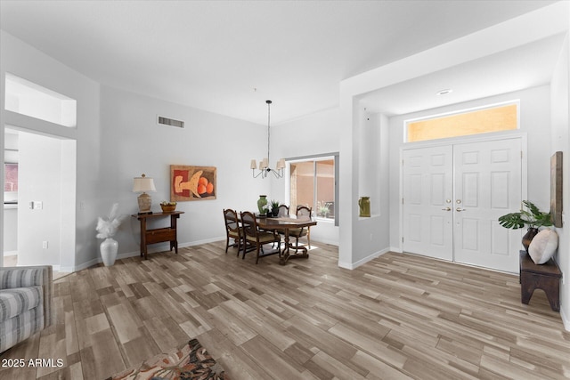 entryway featuring a notable chandelier, visible vents, baseboards, and light wood-style floors