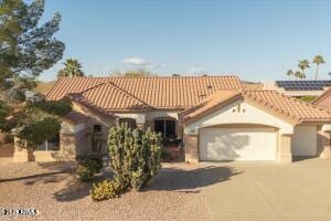 mediterranean / spanish house with driveway, a tile roof, and a garage