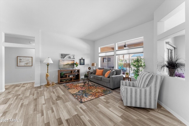 living room with ceiling fan, baseboards, and wood finished floors