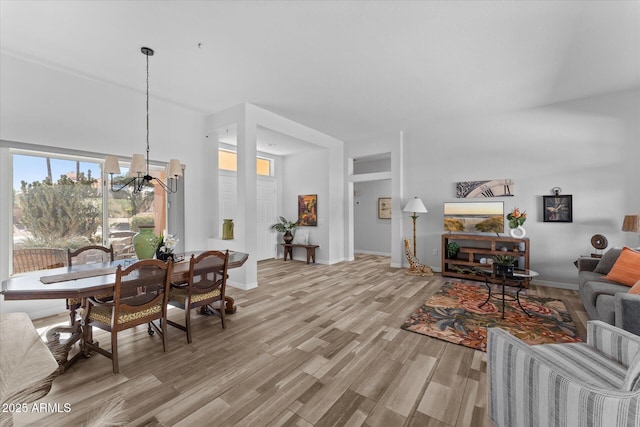 living room with a chandelier, baseboards, and light wood-style floors