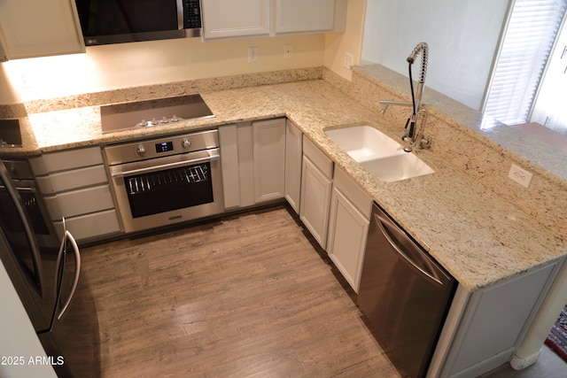 5720 S 21st Ter, Phoenix, AZ 85040 - kitchen featuring stainless steel appliances, a sink, light wood finished floors, light stone counters, and white cabinets