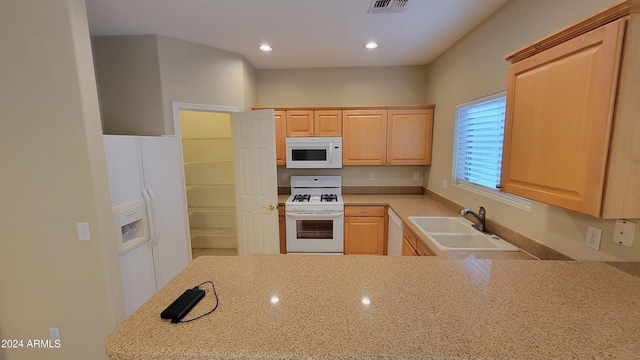 kitchen with kitchen peninsula, light brown cabinets, white appliances, and sink