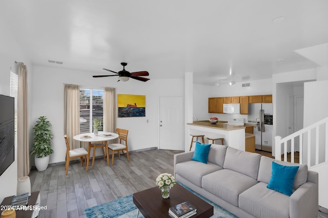 living room with ceiling fan and light hardwood / wood-style flooring