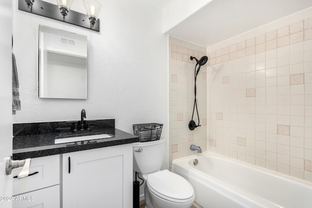 full bathroom with tiled shower / bath, vanity, and toilet