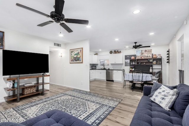 living room featuring light hardwood / wood-style floors, ceiling fan, and sink