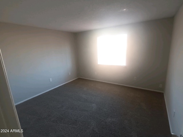 unfurnished room featuring dark colored carpet