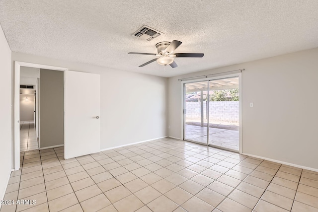 empty room featuring a textured ceiling, light tile patterned floors, and ceiling fan