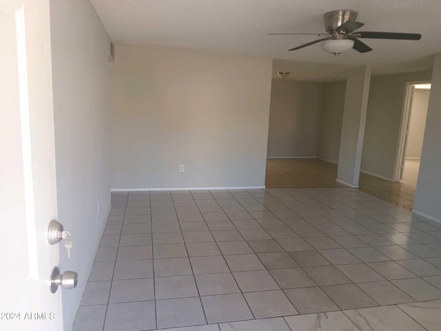 tiled empty room featuring ceiling fan