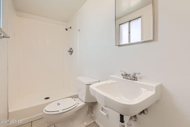 bathroom featuring toilet, a shower, sink, and tile patterned flooring