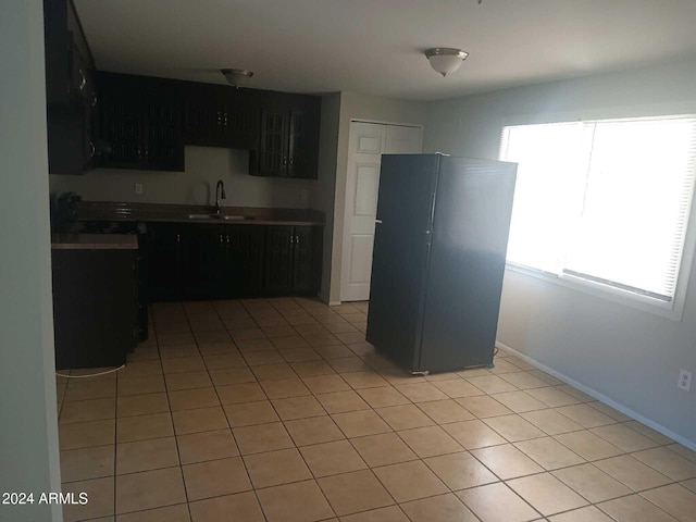 kitchen with light tile patterned floors, sink, and black fridge