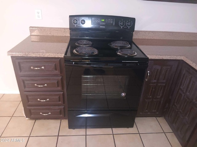 kitchen featuring light tile patterned floors, dark brown cabinetry, and black range with electric stovetop