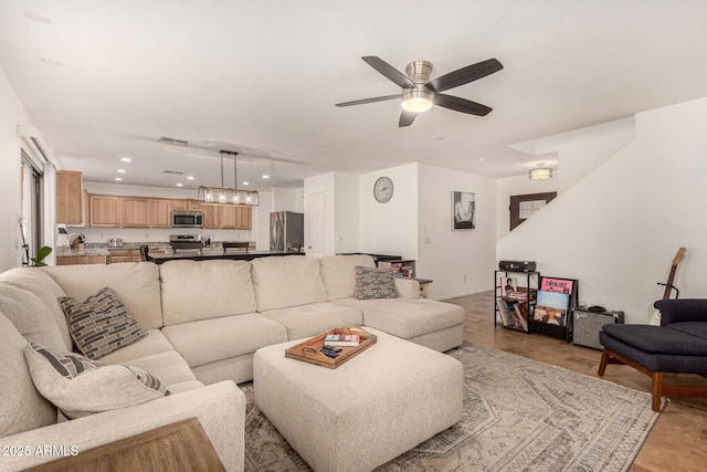 living room featuring ceiling fan with notable chandelier