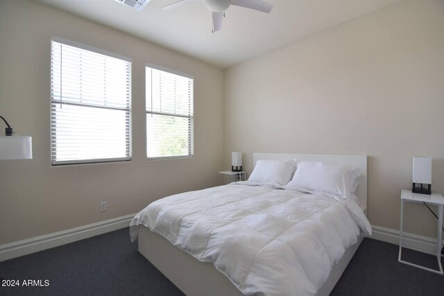 bedroom with multiple windows, ceiling fan, and dark carpet