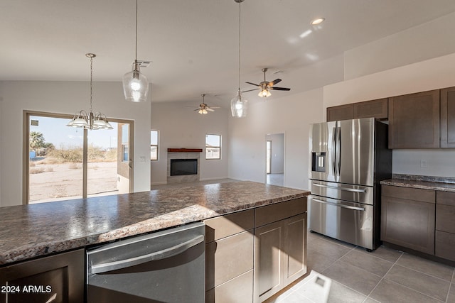 kitchen with dark brown cabinetry, stainless steel appliances, decorative light fixtures, vaulted ceiling, and ceiling fan with notable chandelier