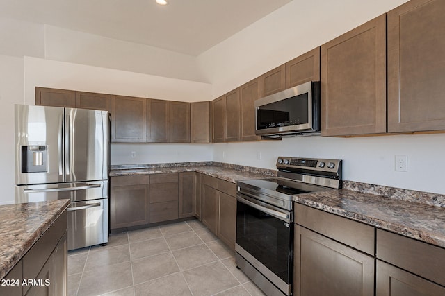 kitchen featuring dark brown cabinetry, light tile patterned floors, and appliances with stainless steel finishes