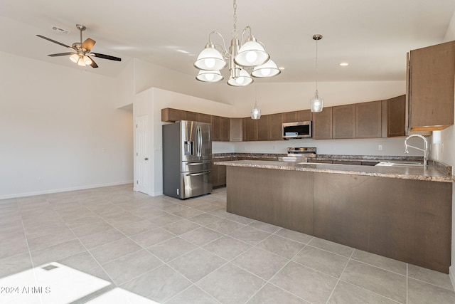 kitchen with sink, stainless steel appliances, pendant lighting, lofted ceiling, and ceiling fan with notable chandelier