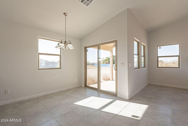 tiled spare room with plenty of natural light, a chandelier, and vaulted ceiling