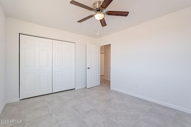 unfurnished bedroom with ceiling fan, a closet, and light tile patterned floors