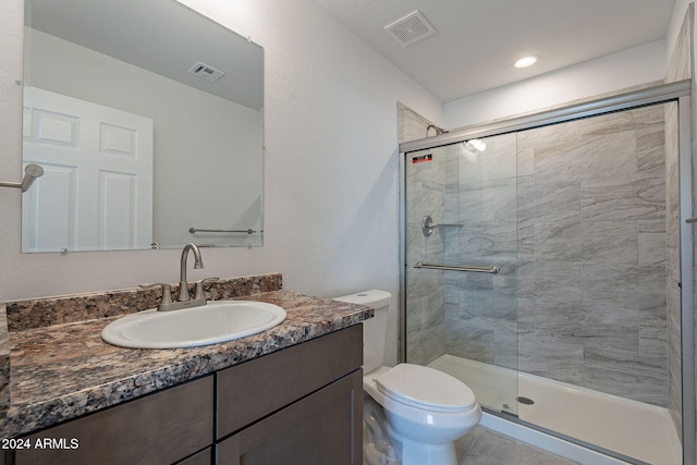 bathroom featuring vanity, a shower with shower door, and toilet